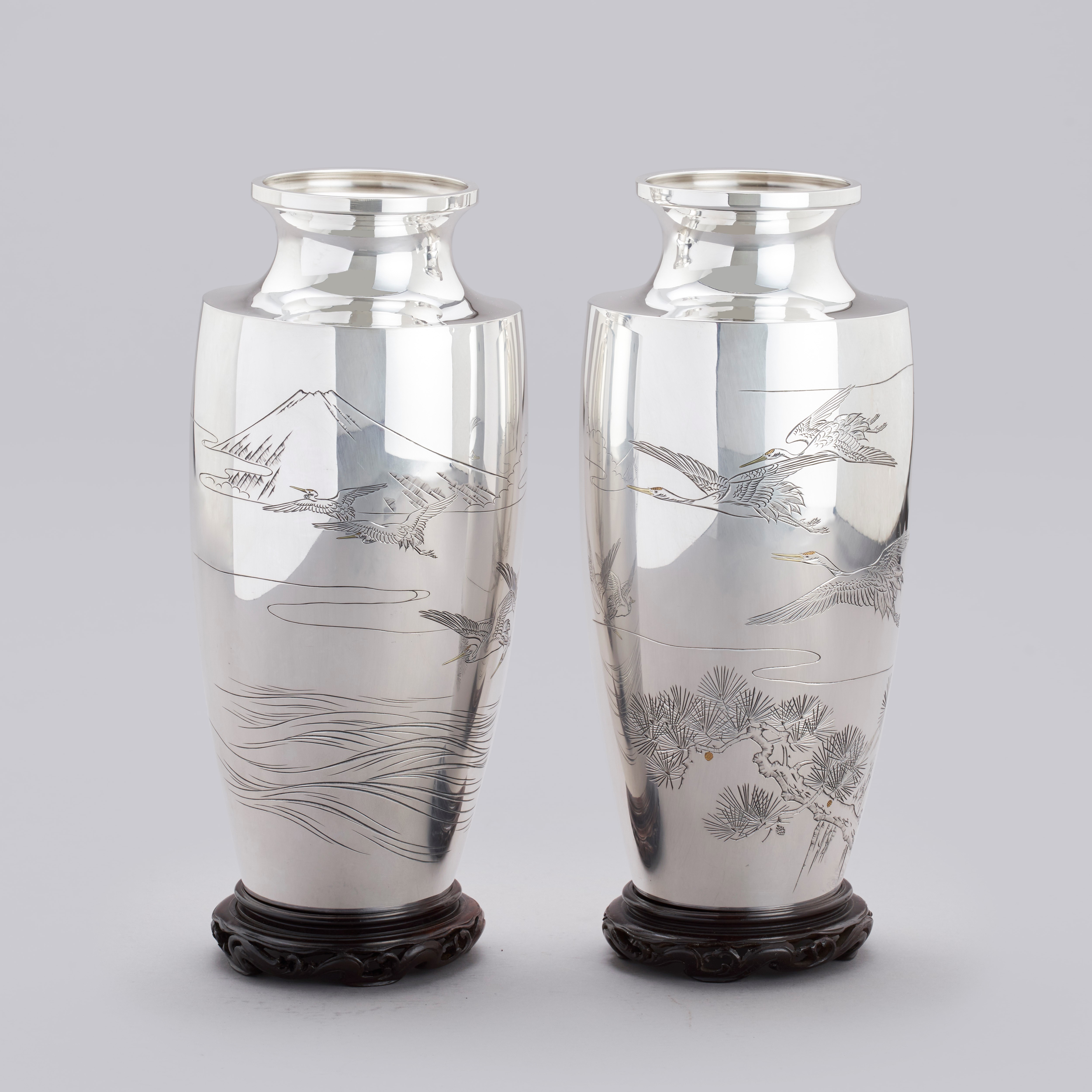 A pair of silver vases with flying Manchurian cranes above pine trees, Taishō period 1912-1926.
